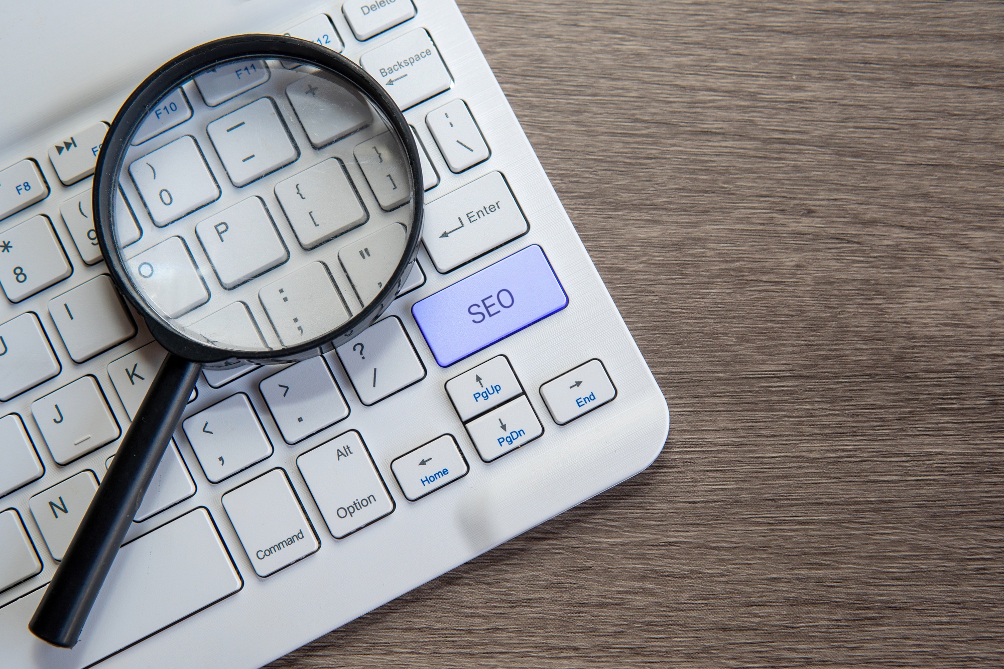 A magnifying glass on a computer keyboard with the letters "SEO".